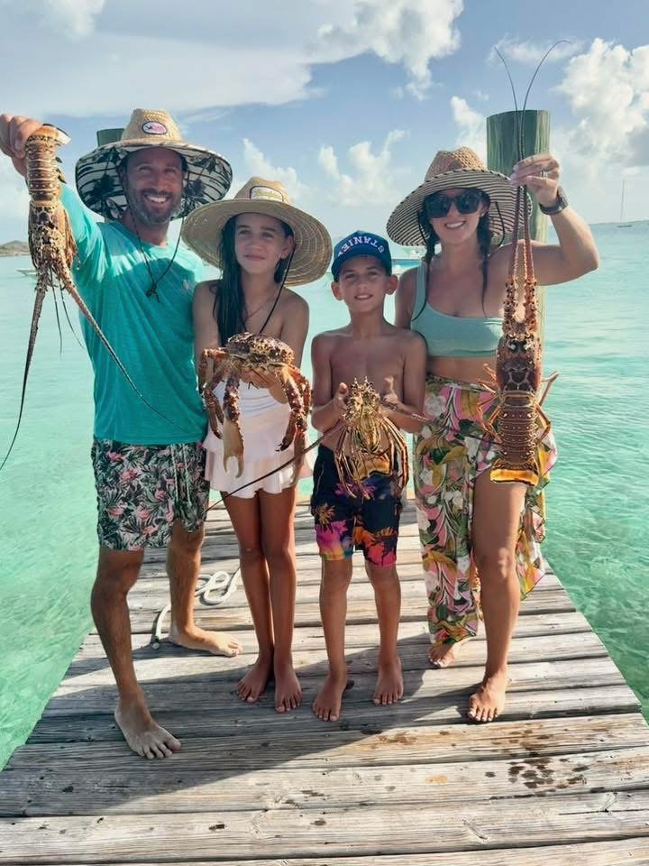 After a long day on the water, picture of my family holding our lobster and crab catch on Staniel Cay Yacht Club dock